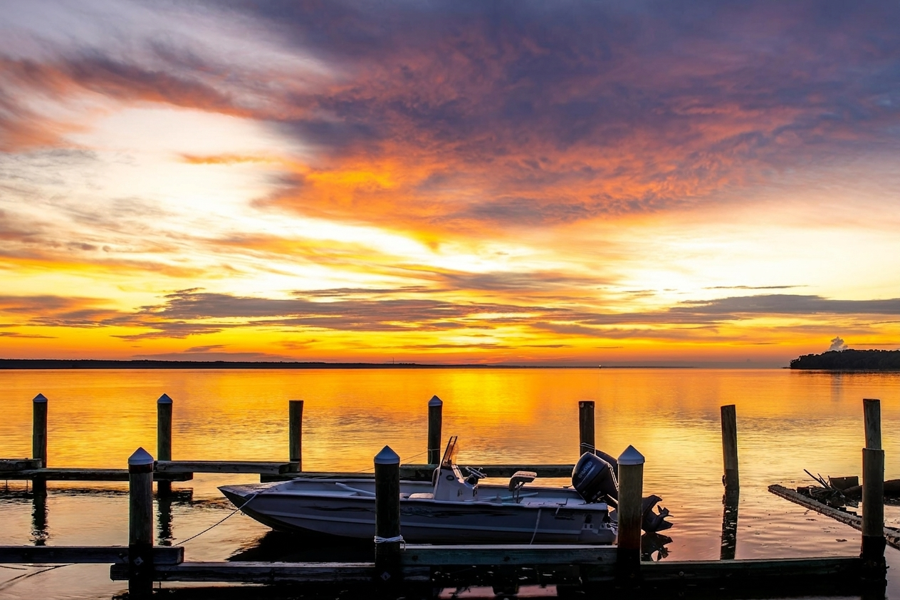 A vivid Gulf Coast sunset over calm water at a wooden dock