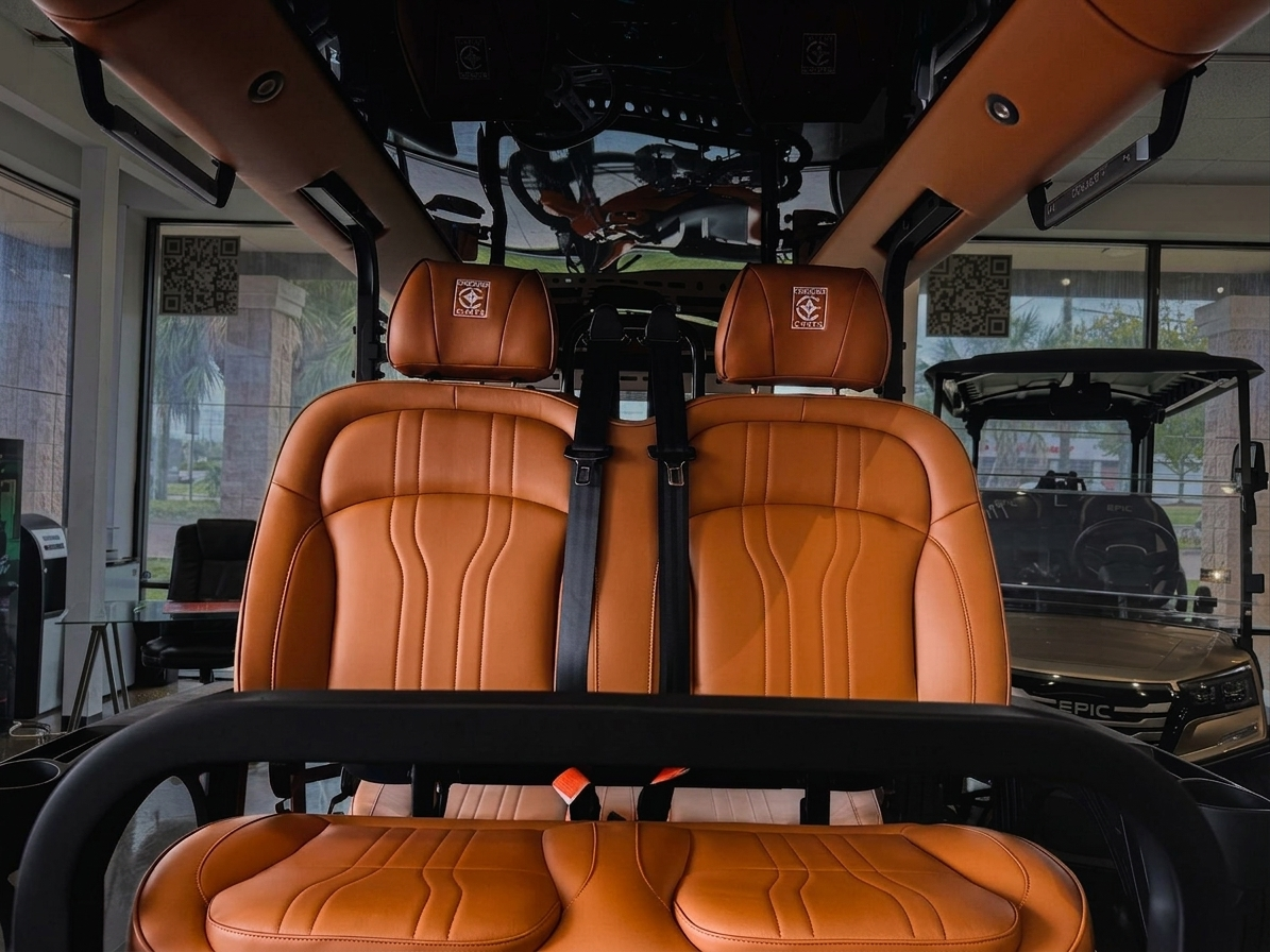 Cognac saddle-leather bucket seats with seat belts inside an electric cart